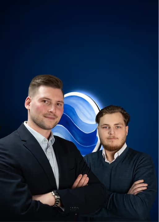 Zwei Kollegen von OPTIMEDIA vor dem beleuchteten Firmenlogo